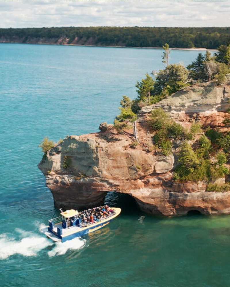 The jet boat speeding past a forested sandstone point