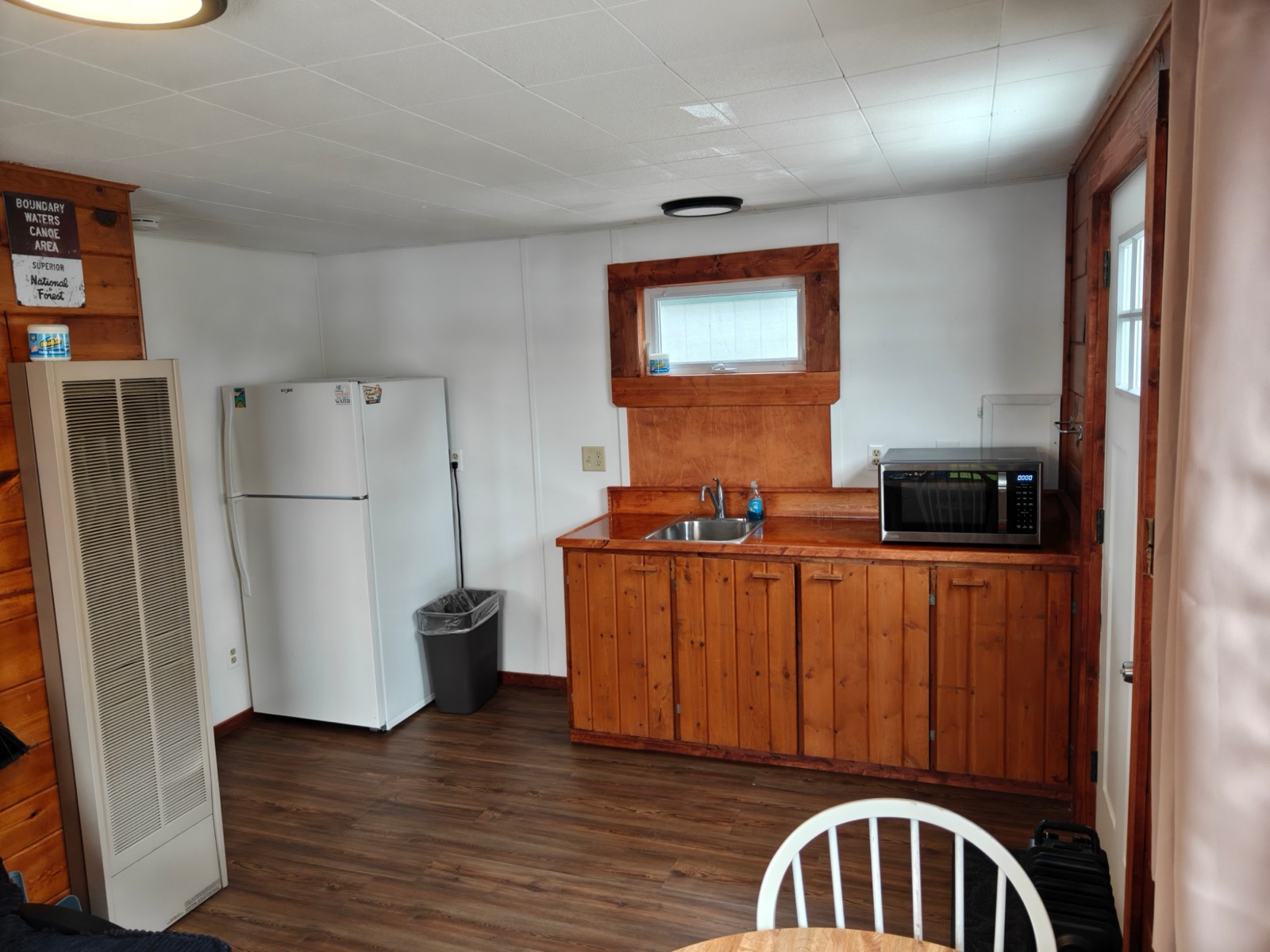 The kitchenette: a fridge, a sink in a wooden counter and a microwave