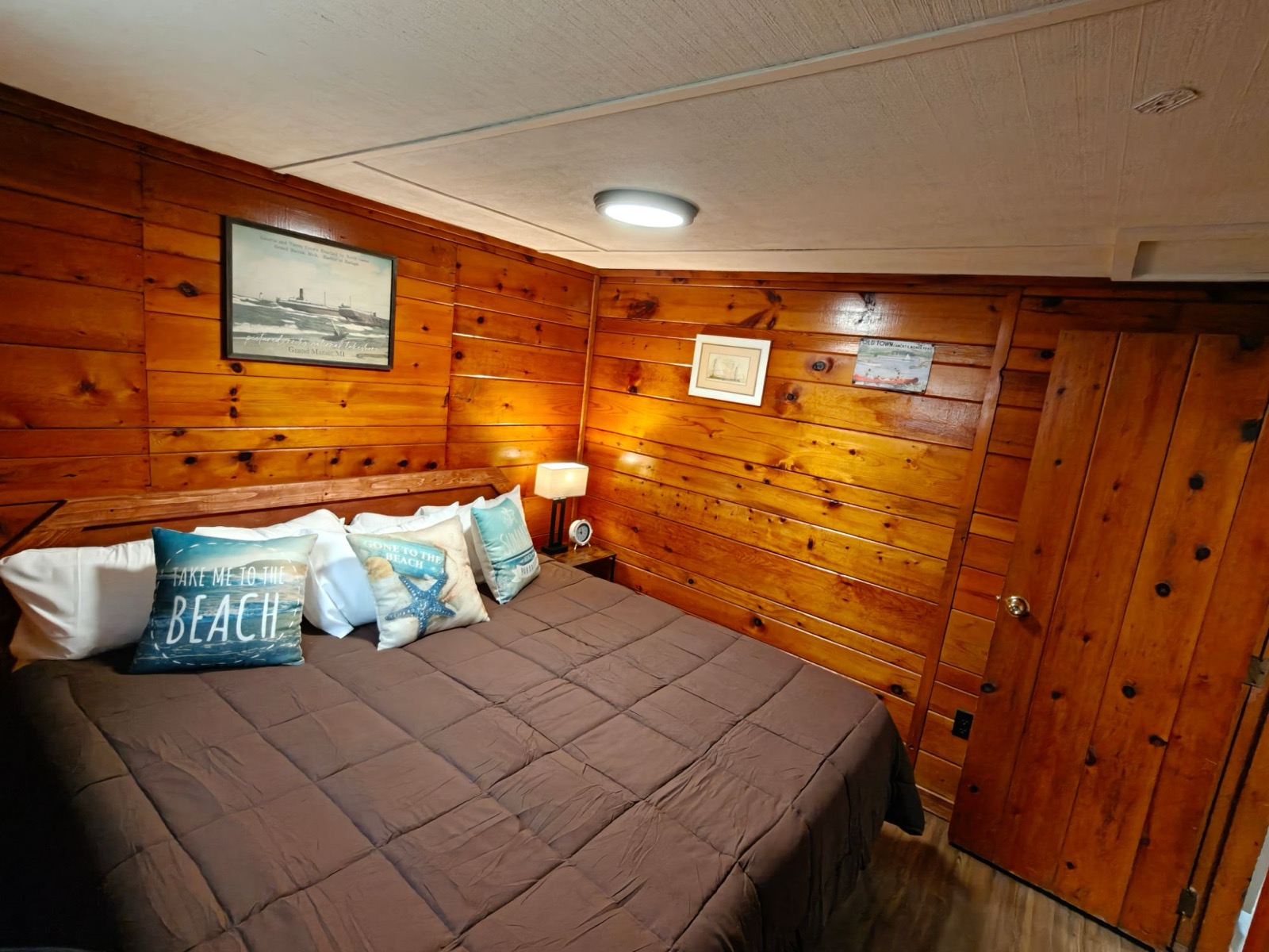 The big bedroom: a king bed with beach cushions under knotty pine walls