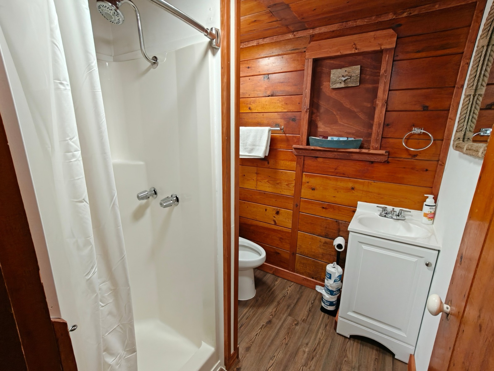 The bathroom: a shower, a small vanity and pine walls