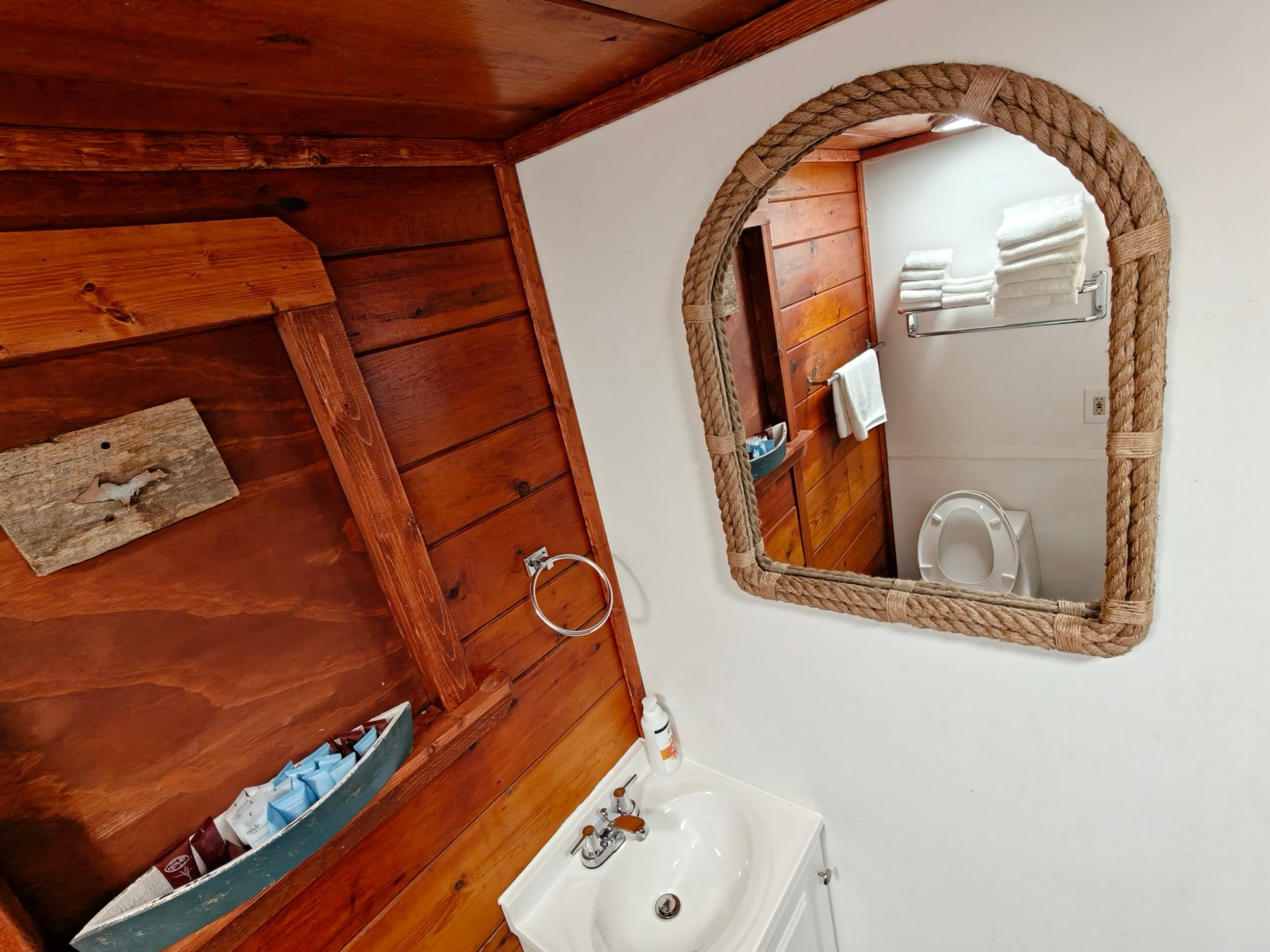 A rope-framed mirror over the sink and a boat full of soaps