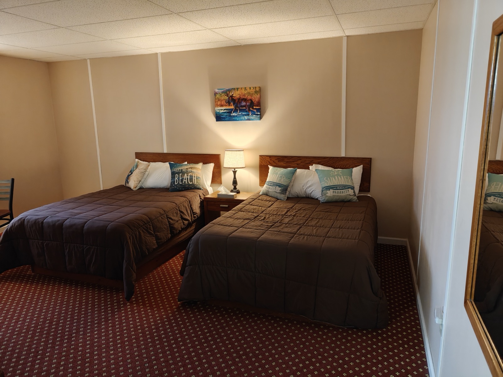 Two double beds with lamps and art above them in a motel room