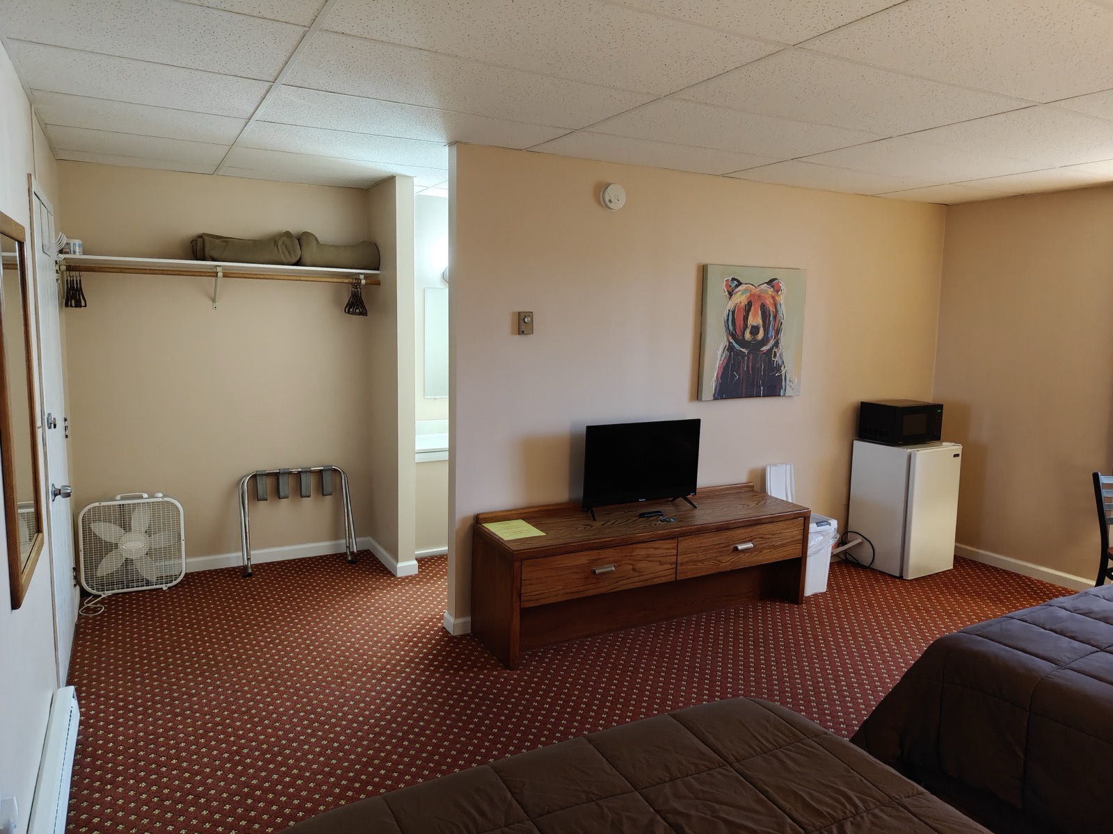 A desk with a TV, a mini fridge and a microwave, the closet rack beside them