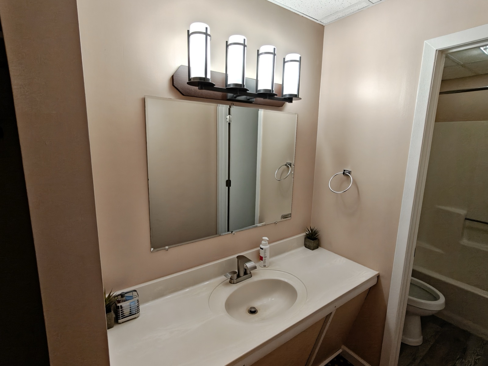 The bathroom vanity with a mirror and lights, the shower and tub behind