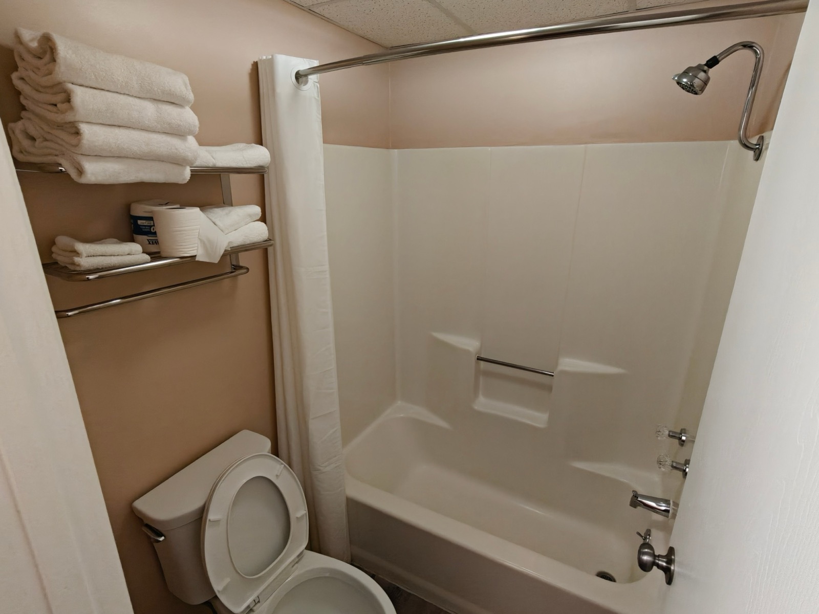 The bathroom: a tub with a shower, fresh towels on the rack and a toilet
