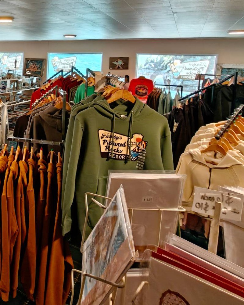 Fletchy's hoodies on the rack in the gift shop, jewelry and bags on the table beside them