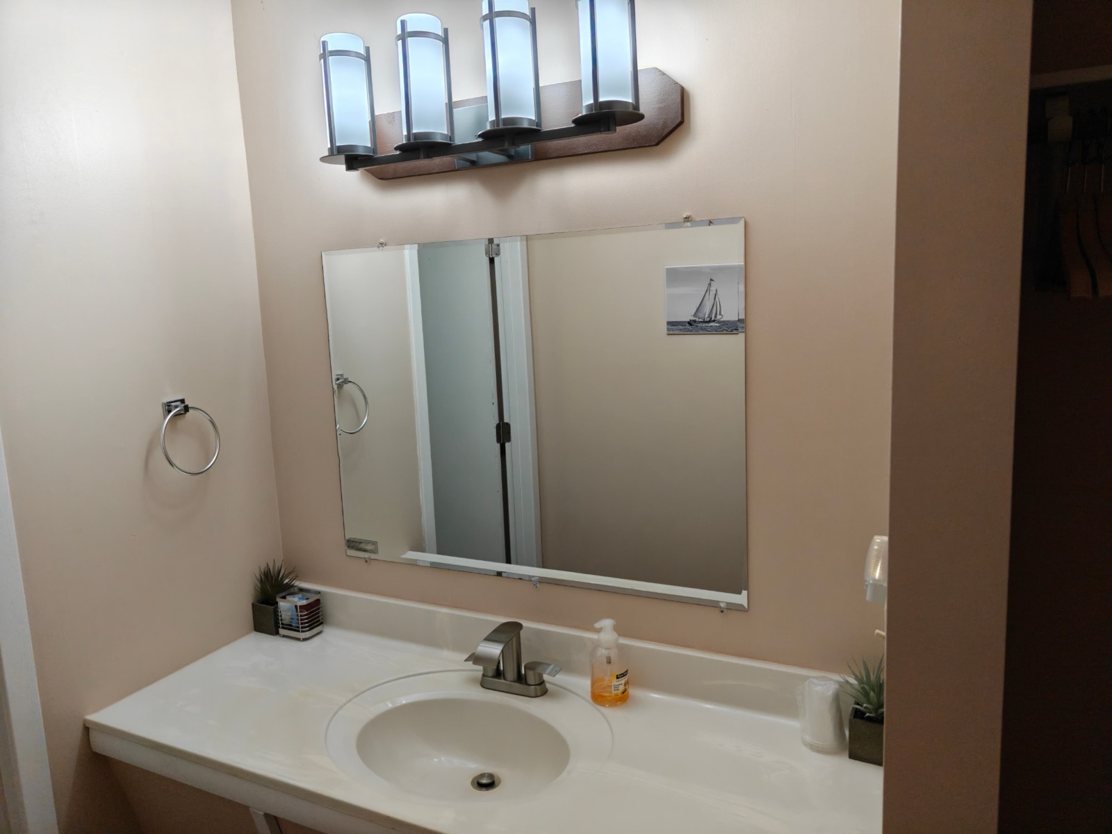 The bathroom vanity with a wide mirror and four lights