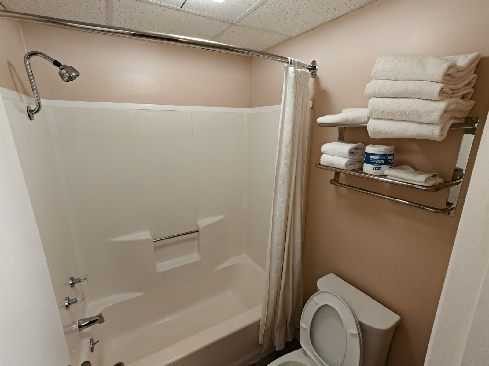 The tub and shower, fresh towels stacked on the rack