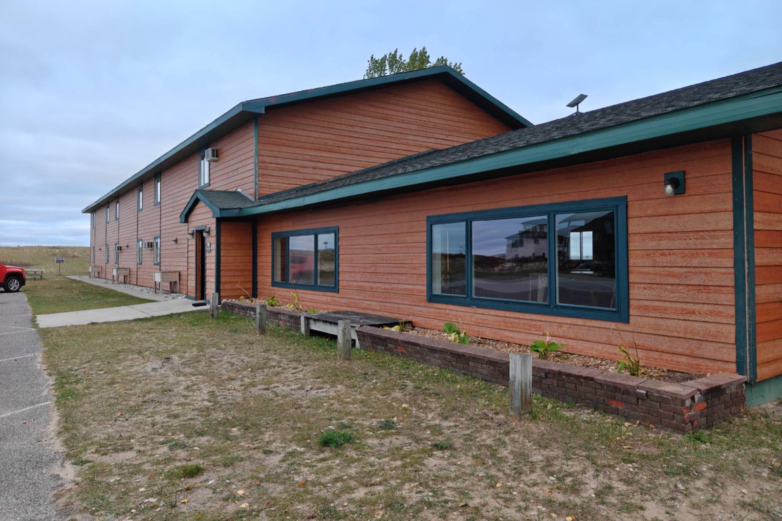 The two-storey motel in cedar-red siding with green trim, the lobby wing in front