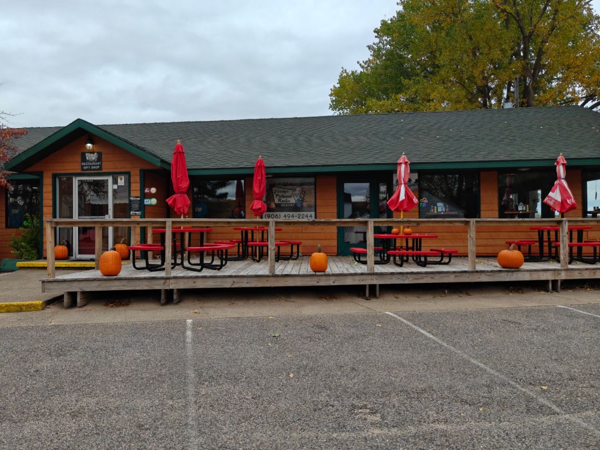 The restaurant and gift shop: a wooden deck with red picnic tables and umbrellas, pumpkins by the steps