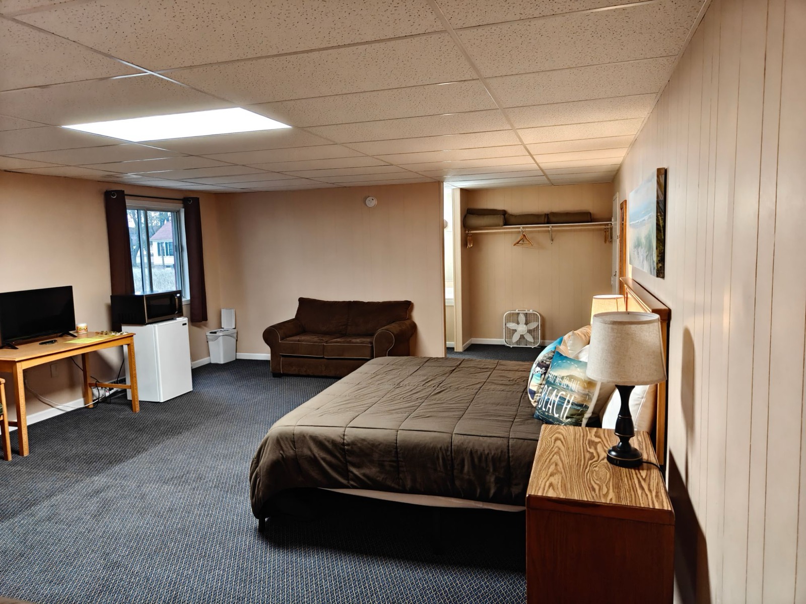 The king bed, a sofa, a desk with a TV, a mini fridge and microwave by the window