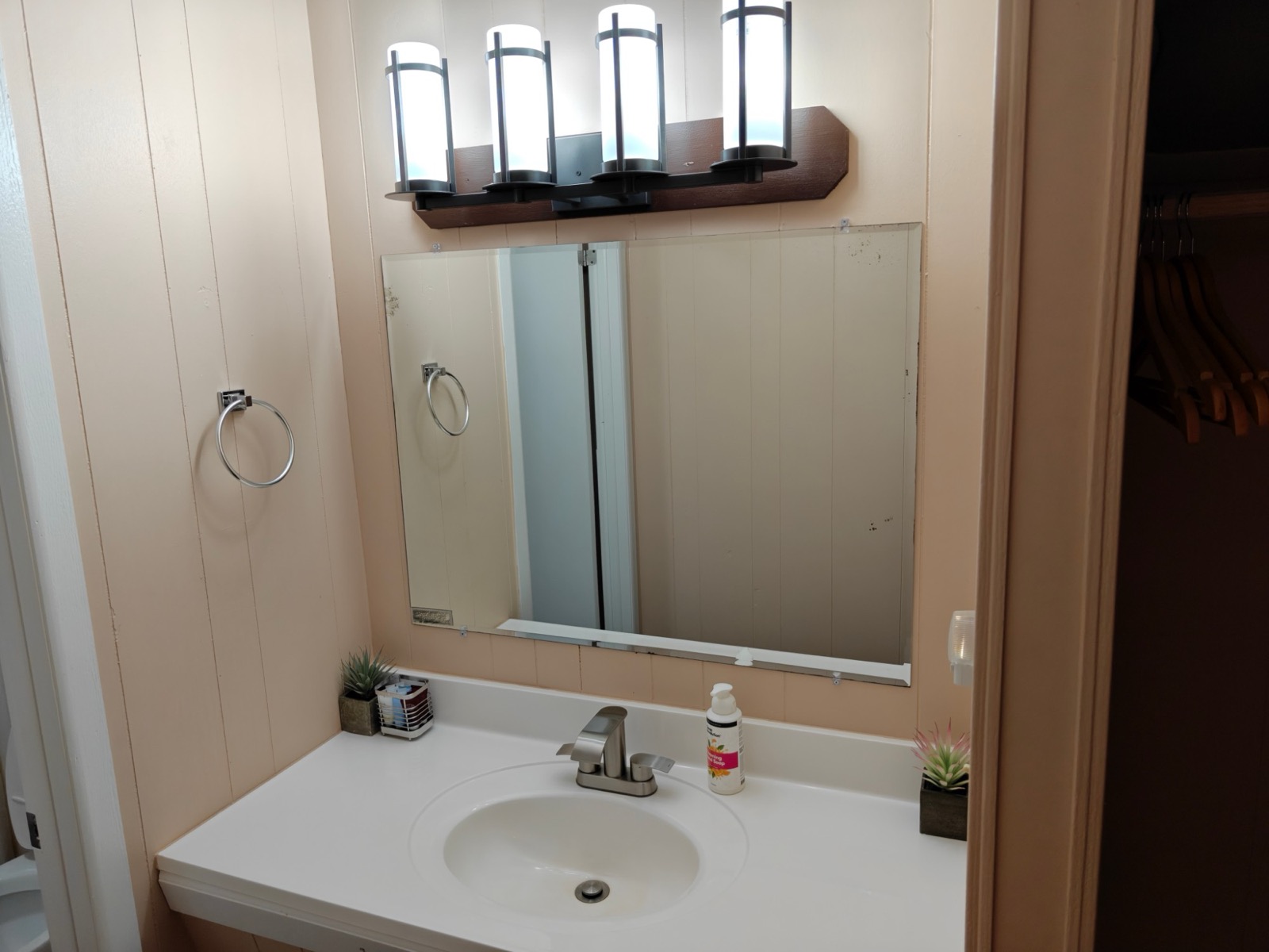 The bathroom vanity with a wide mirror and four lights