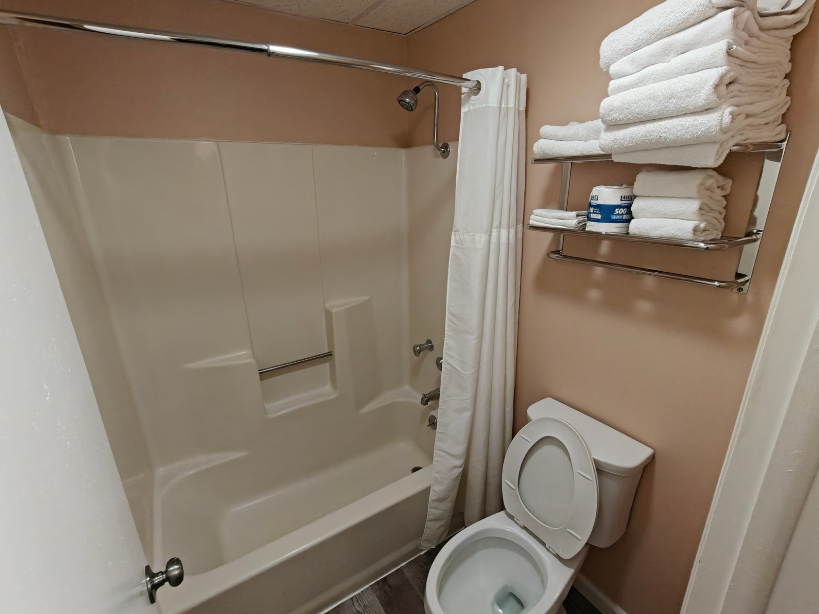 The tub and shower, fresh towels stacked on the rack